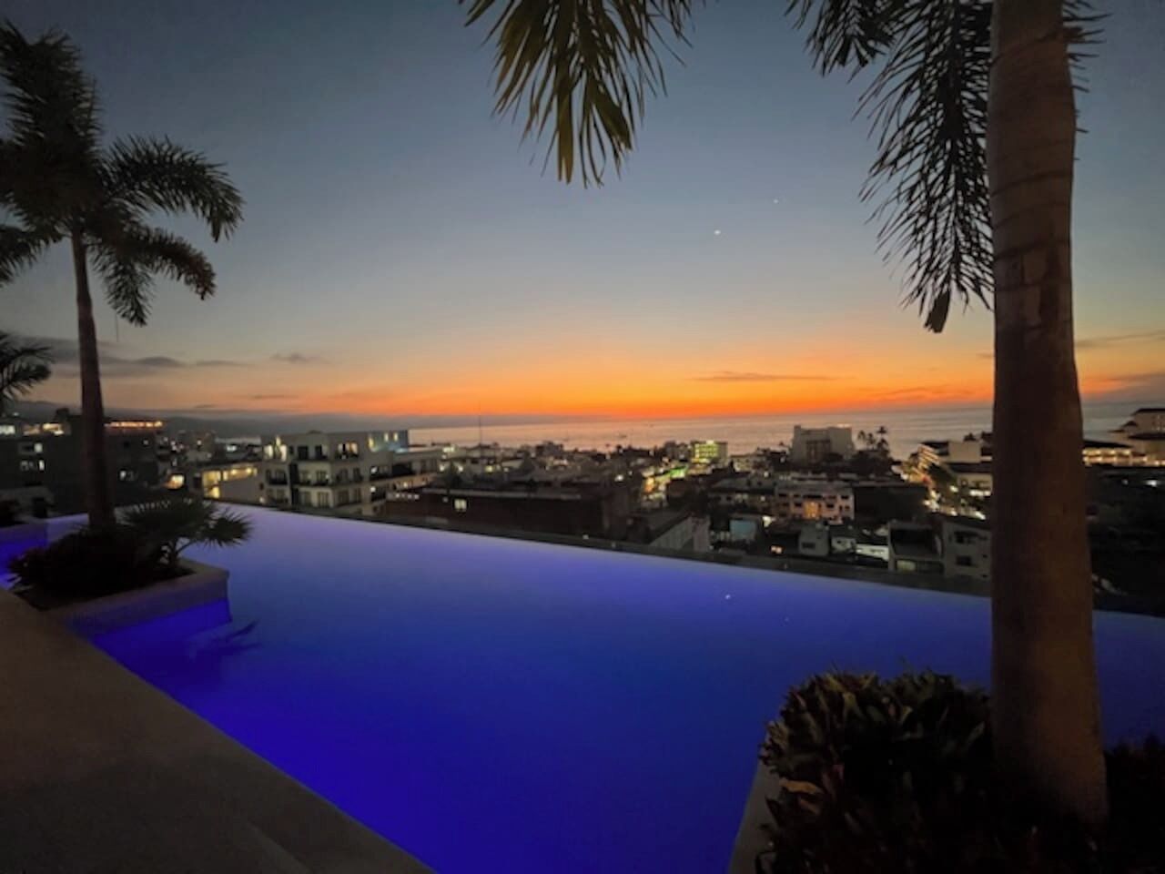 Ein Rooftop-Endlospool mit Blick auf die Skyline im Abendlicht.