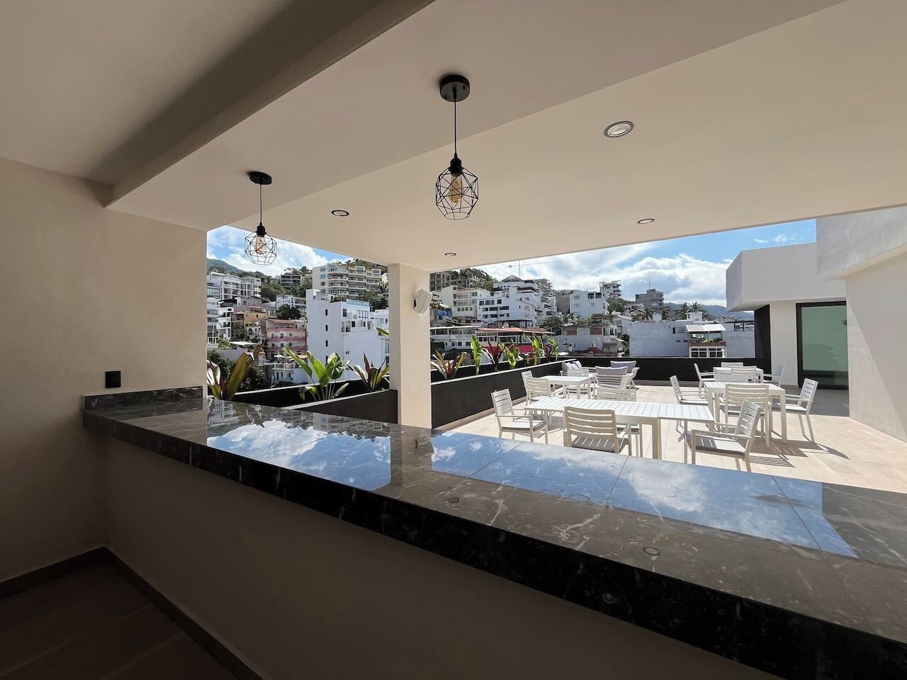 Eine moderne Küche mit Marmorarbeitsplatte und Blick auf eine Dachterrassen-Sitzgelegenheit.