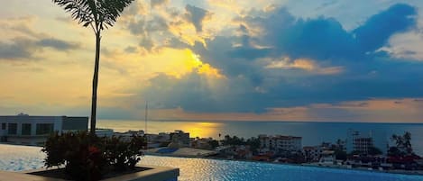 Una piscina con vistas al mar y edificios al fondo.