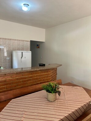 Eine Küche mit einer Ziegel-Arbeitsplatte, einem weißen Kühlschrank und einem kleinen Blumentopf.