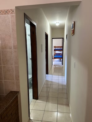 A hallway with a tiled floor, a wooden door, and a view into a room with a bunk bed. - Vacation home in Ubatuba, SP (Ubatuba)