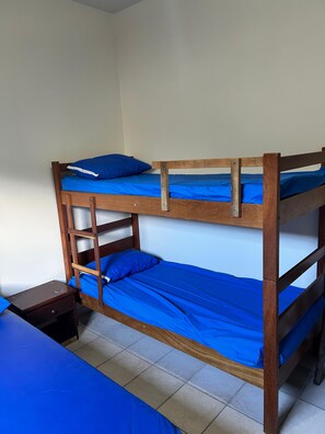 Ein Etagenbett mit blauer Bettwäsche und einem kleinen Nachttisch.
