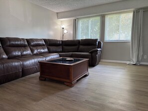 A living room with a brown leather sectional sofa, a wooden coffee table, and a floor lamp. - Spacious 4-bedroom house with AC in enchanting Columbus (Columbus)