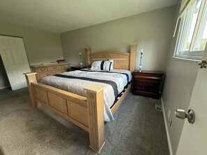 Ein Schlafzimmer mit einem Holzbett, einem Nachttisch, einer Kommode und einer Tür.
