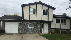 Ein zweistöckiges Haus mit Garage, Eingangstür und Auffahrt.