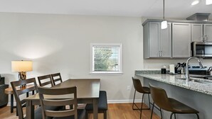 A modern kitchen with grey cabinets, a stainless steel sink, and a granite countertop. - Superb Southside Townhome (Asheville)