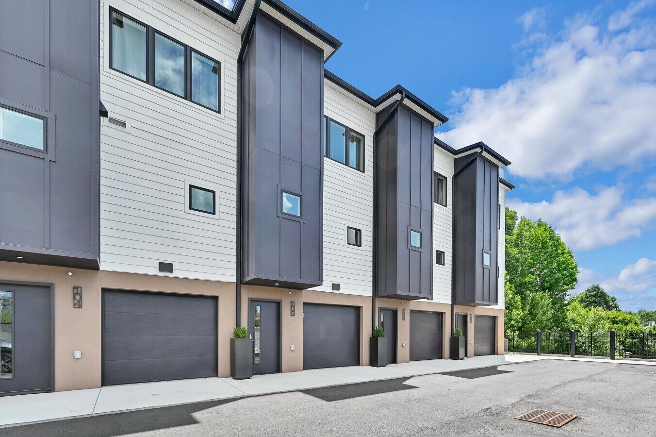 Un immeuble résidentiel moderne à plusieurs étages, doté de grandes fenêtres, de portes de garage et d’un toit plat.