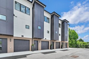 A modern multi-story residential building with large windows, garage doors, and a flat roof. - Superb Southside Townhome (Asheville)