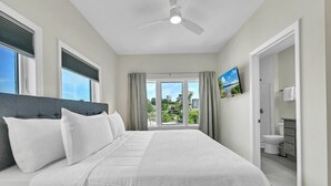 A bedroom with a bed, a ceiling fan, a television, and a view of the outdoors. - Superb Southside Townhome (Asheville)