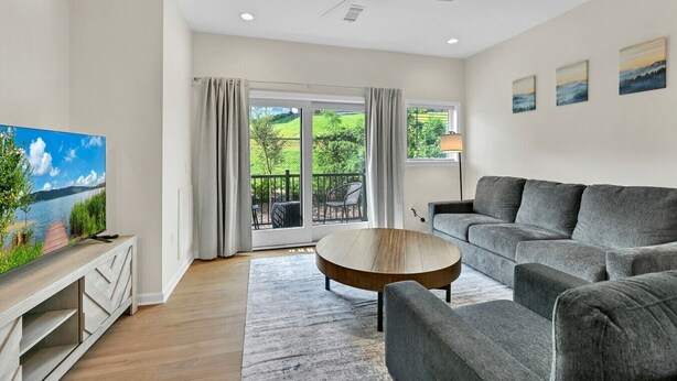 A modern living room with a grey sofa, a round coffee table, and a television on a wooden stand. - Superb Southside Townhome (Asheville)