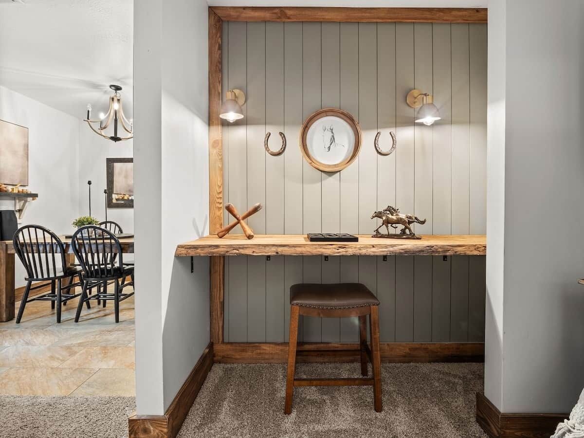 Een hoekwerkplek met een houten bureau, een kruk en wandlampen.