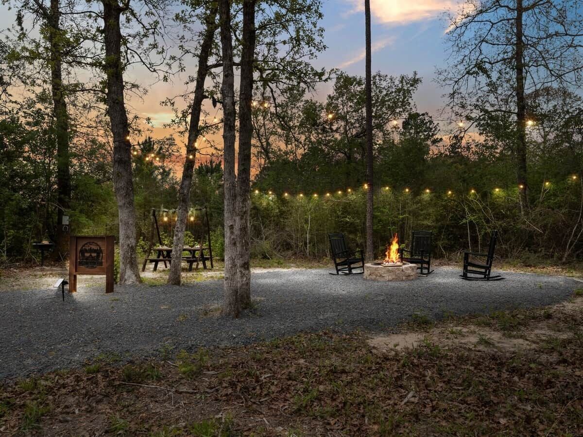 A campsite with a fire pit, benches, and string lights.