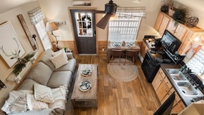 A compact living space with a sofa, coffee table, dining table, kitchen area, and a ceiling fan.