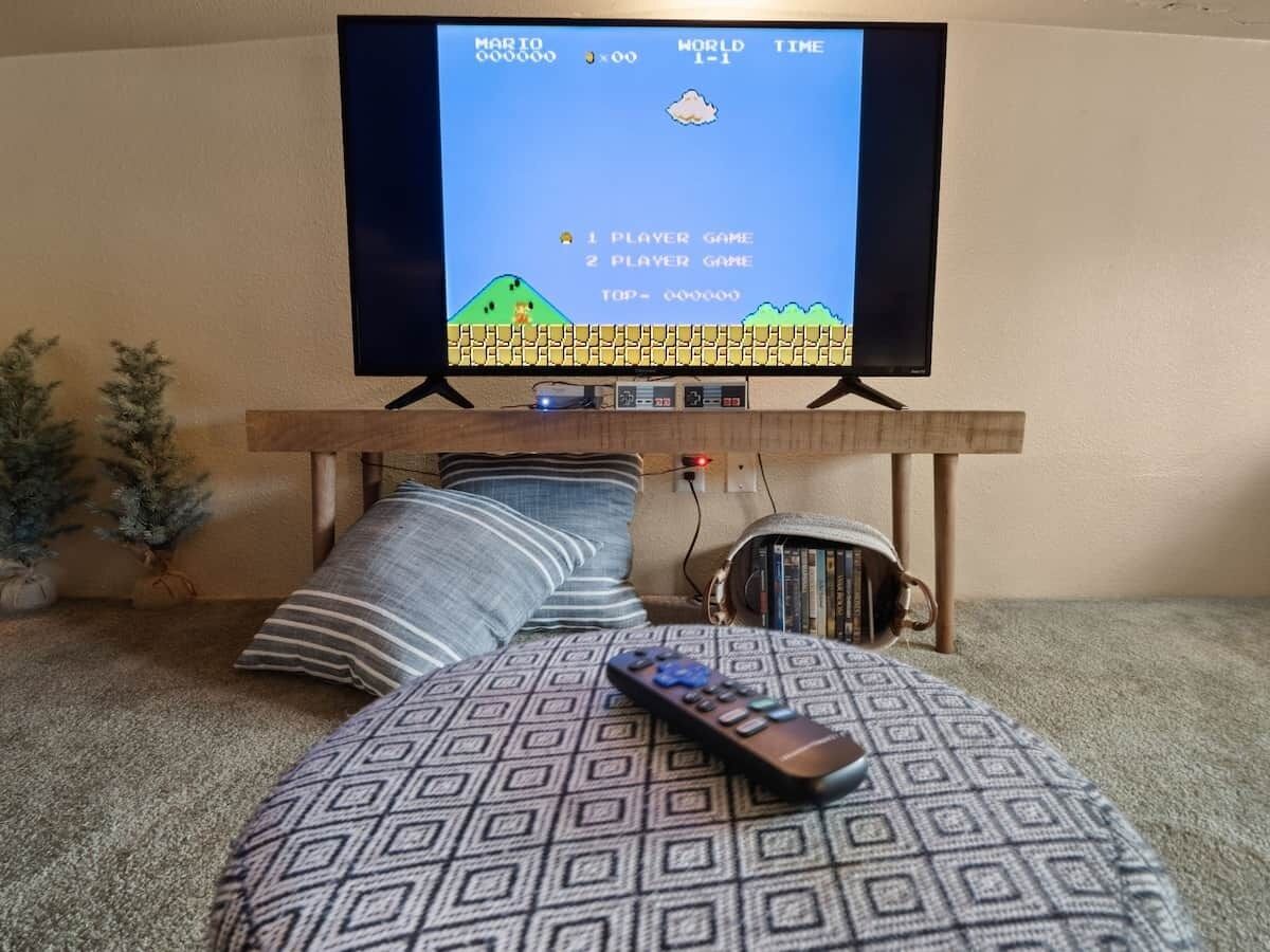A bedroom with a bed, a television on a stand, a remote control, and a bookshelf.