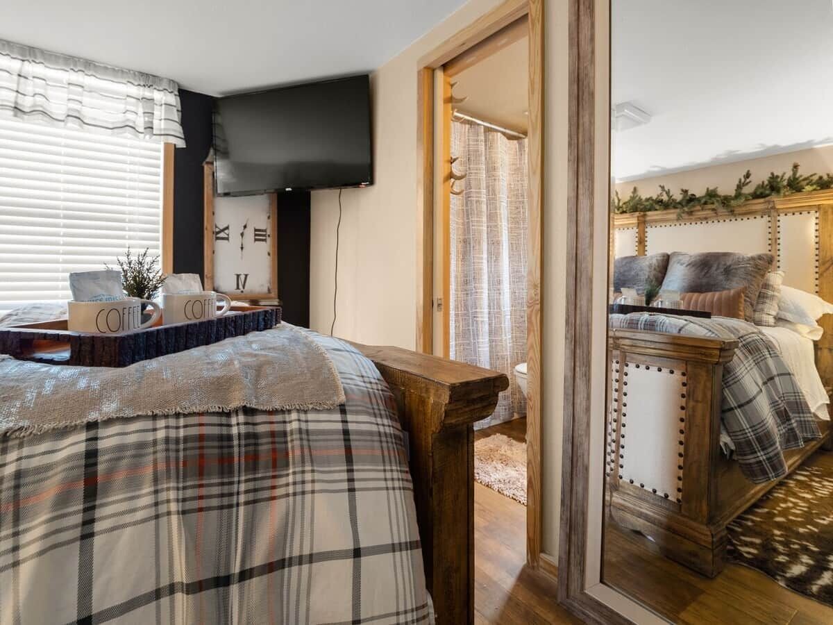 A bedroom with a bed, a bedside table, a mirror, and a television.