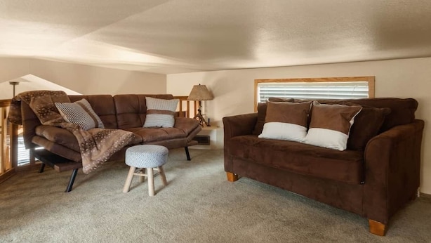 A cozy living room with a brown sofa, a matching armchair, and a small ottoman.