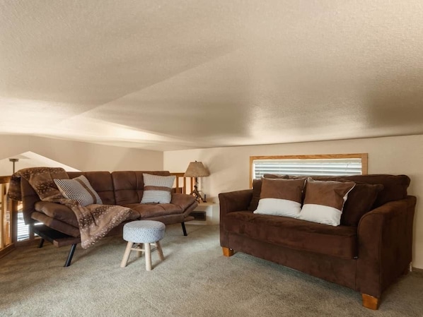 A cozy living room with a brown sofa, a matching armchair, and a small ottoman.