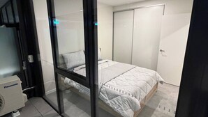 Un dormitorio con cama, armario y aire acondicionado Panasonic.