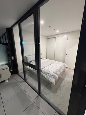 A bedroom with a bed, a wardrobe, and a Panasonic air conditioner. - Brand new G6 Apartment (Canberra)