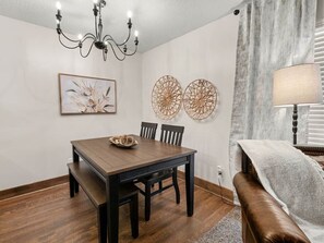 Un comedor con mesa de madera, sillas, una lámpara de araña y adornos en la pared.
