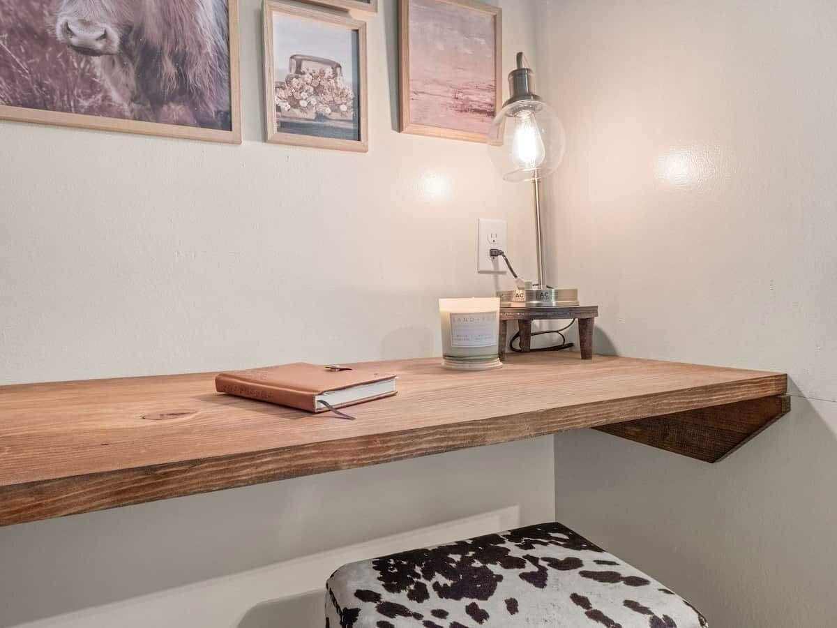 Une étagère en bois avec un livre, une bougie et une lampe.