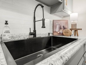 Een keukenkraan met een modern design, een fles handzeep en een decoratief object op het aanrecht.