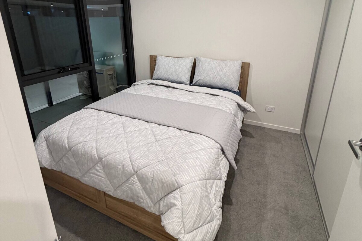 A bedroom with a bed, a window, and a door.