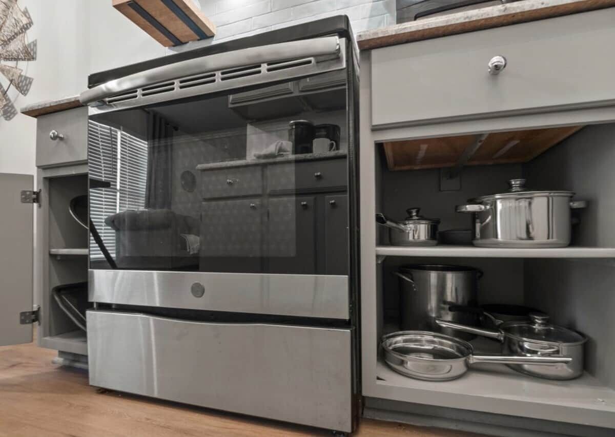 Une cuisine compacte dotée d’un four encastré et d’étagères de rangement.