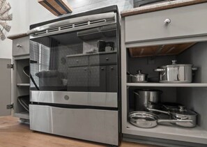A compact kitchen with a built-in oven and storage shelves.