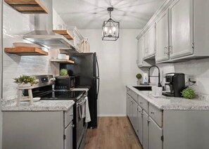 A compact kitchen with a central island, built-in appliances, and a hanging light fixture.