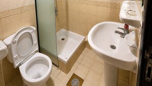 Un baño con inodoro, cabina de ducha, lavamanos y un perchero para toallas.