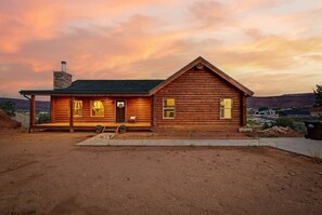 A log cabin with a porch, a chimney, and a view of the landscape. - Cliffrose Cabin | Panoramic Views, Near Zion, BBQ, 2min to Downtown! (Kanab)