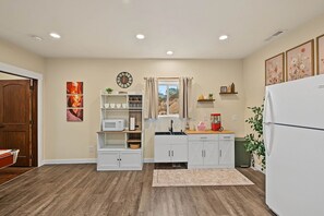 A compact kitchen with white cabinetry, a microwave, a sink, and a refrigerator. - Cliffrose Cabin | Panoramic Views, Near Zion, BBQ, 2min to Downtown! (Kanab)