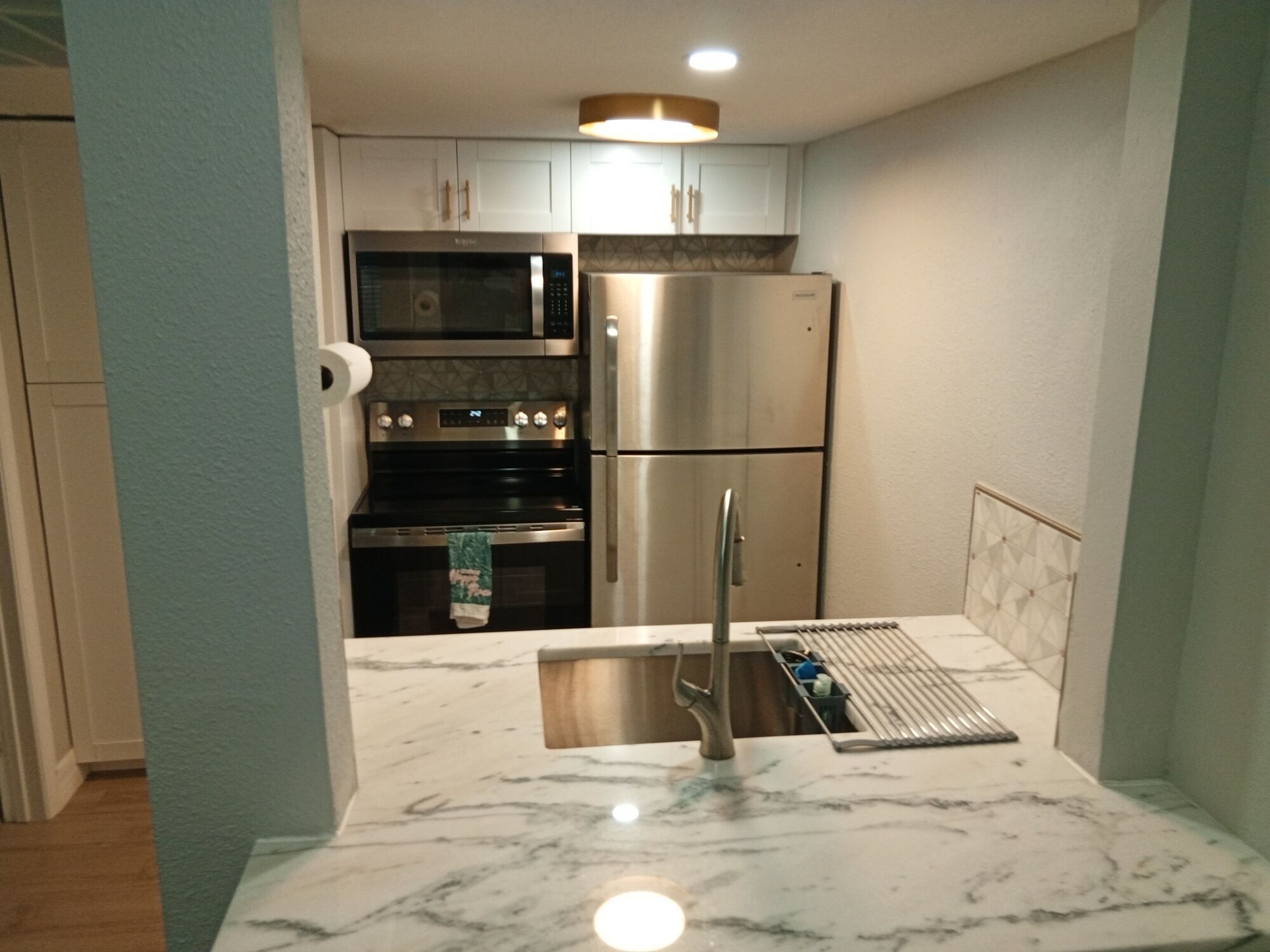 A compact kitchen with a stainless steel refrigerator, a microwave, and an oven.