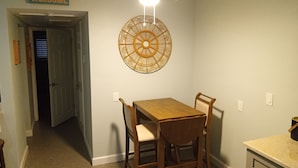 Uma área de refeições com mesa e cadeiras, ventilador de teto e um objeto decorativo na parede.