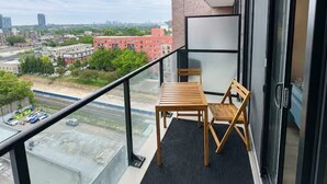 Ein Balkon mit Tisch und Stühlen, eine Glastür und Blick auf die Stadt.