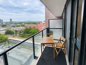 Un balcone con tavolo e sedie, una porta in vetro e vista sulla città.