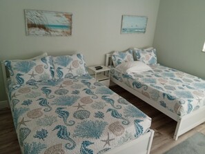 Een kamer met twee bedden, elk met een beddekleed met een patroon, een klein nachtkastje en een aan de muur hangend kunstwerk.