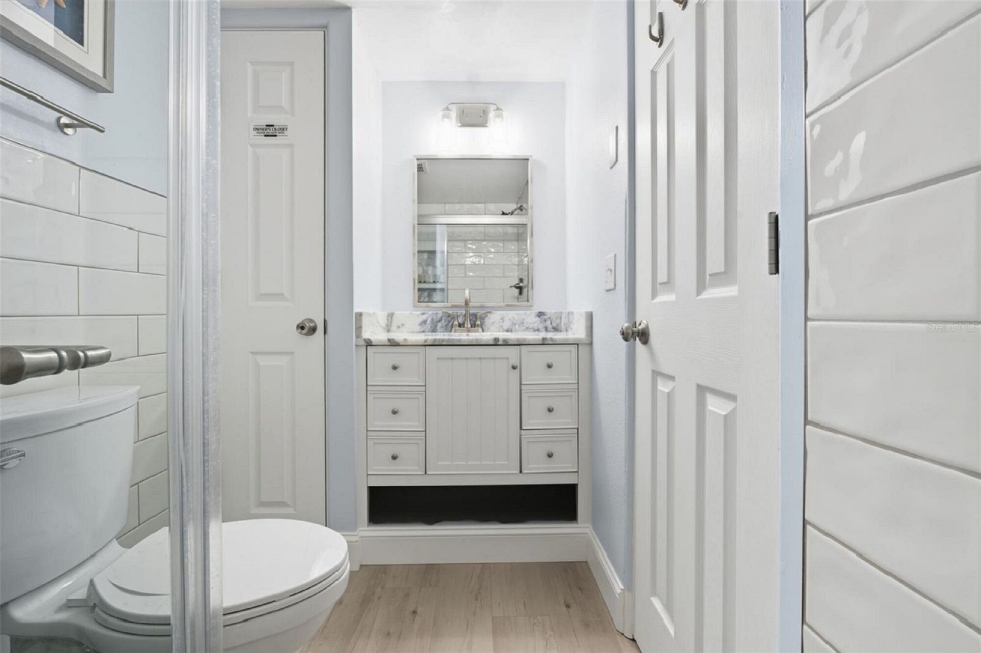Un bagno compatto con un WC, un lavandino con specchio e un mobile.