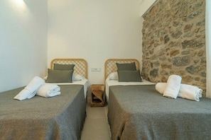 A room with two single beds, each with a wooden headboard and a small wooden stool between them. - Beautiful House in Álora with Pool and Views (Álora)