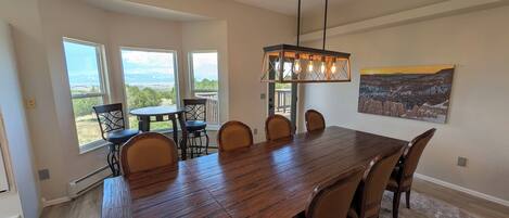 A dining area with a large wooden table, six chairs, and a pendant light.