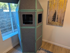 Una habitación con una estructura tipo casa de juegos, una ventana y un cuadro en la pared.