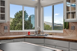 A kitchen with a large window, a sink, and a countertop.