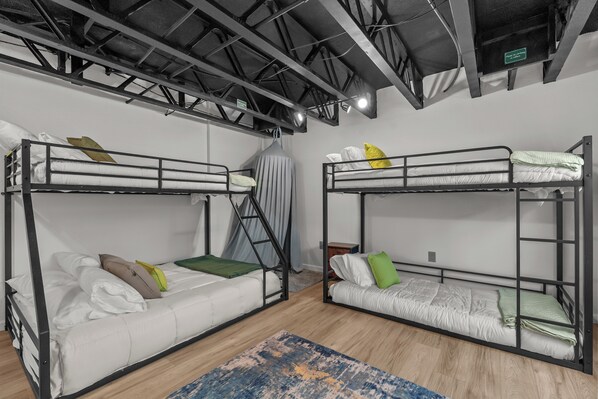 A bunk bed room with a wooden floor, metal bunk beds, and a grey curtain.