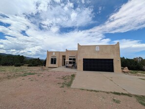 Um edifício moderno de dois andares com garagem, pátio e vista para a paisagem ao redor.