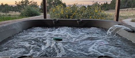 A hot tub with water flowing, surrounded by a wooden deck and a signboard.