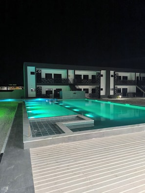 A swimming pool with a modern design, surrounded by a building with multiple balconies and a covered area. - Cozy apartment on Coroa Vermelha Beach (Porto Seguro)