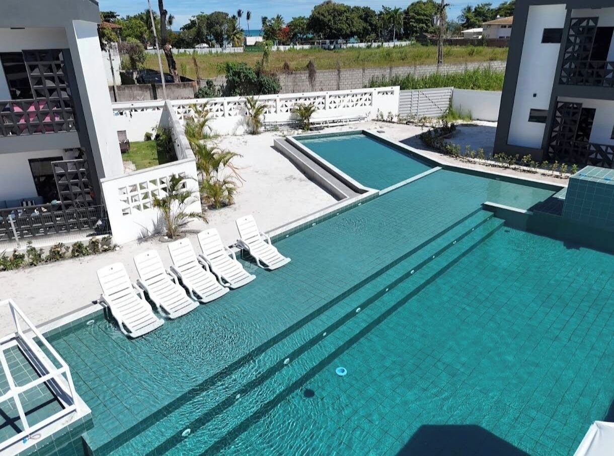 A swimming pool with multiple lanes, surrounded by white walls and a white fence.