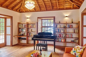 Une pièce chaleureuse avec un grand piano, des étagères en bois et une grande fenêtre.