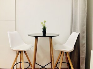 A small round table with a potted plant, flanked by two white chairs with wooden legs. - Central 1 BR Apartment on Alexanderplatz (Berlin)